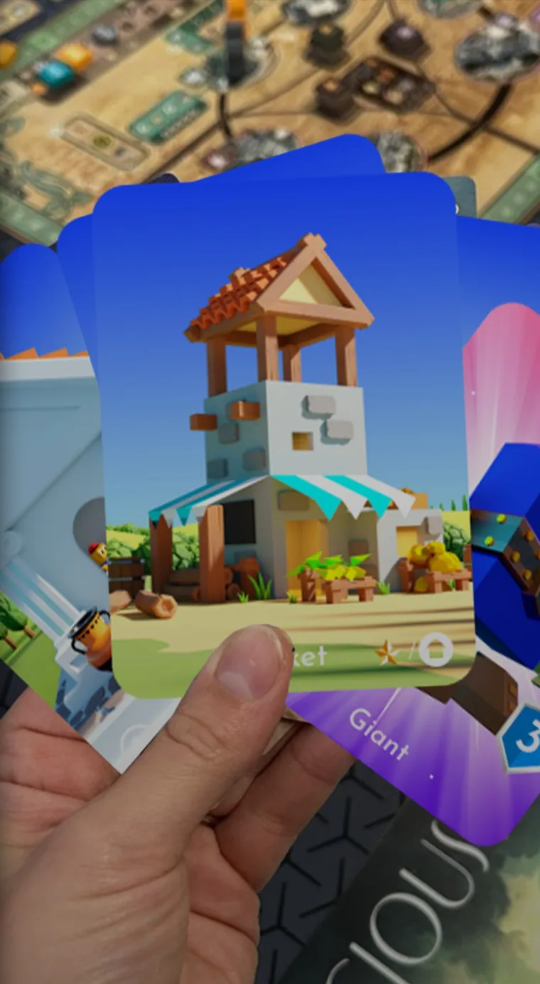 A hand holding Polytopia Empire playing cards over a game table